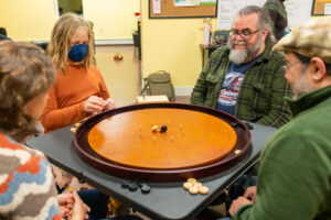 Crokinole ! Libby and Sean vs Peter and Danny. (Tim captures a disk in mid-flight - a true professional !
